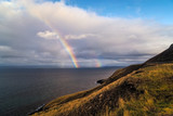 A double rainbow rises over the ocean in Iceland