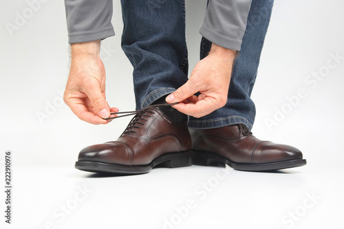 Man tying shoelaces on classic brown Oxford shoes