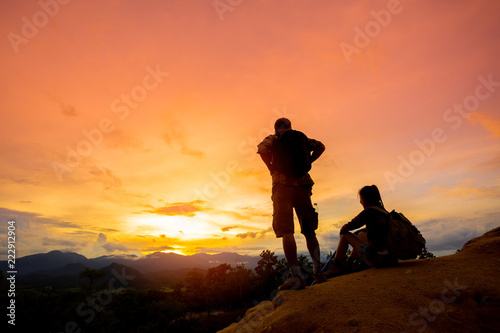 Hikers with backpacks relaxing on top of a mountain and enjoying valley view