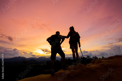 Hikers with backpacks standing on top of a mountain and enjoying sunrise © doidam10