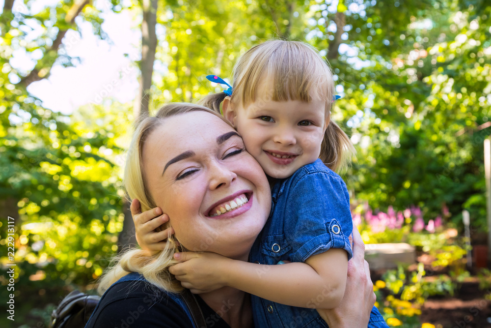 Fototapeta premium Cute blonde woman and her daughter have fun in the park