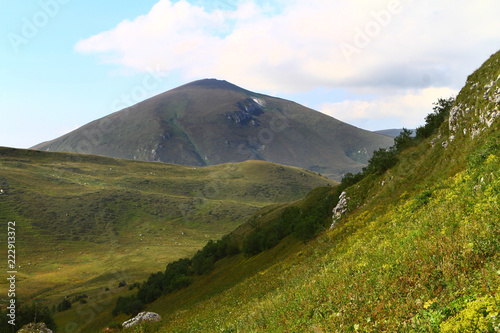 wonderful mountain slope natural landscape photo with green meadow on blue sky background