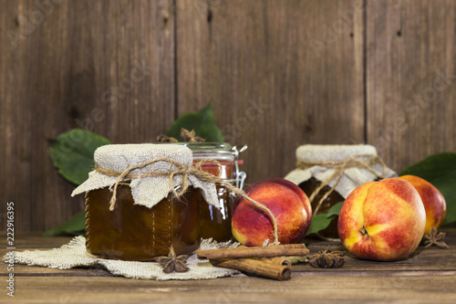Food. Homemade canned fruit in cans. Fruit peach jam and fresh ripe peaches on the background of a wooden table in a rural style