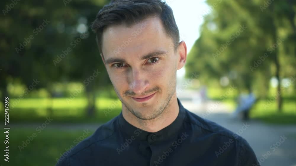 Portrait of attractive man smiling outdoor at sunset In city park. Cute caucasian brunette guy Portrait of attractive man smiling outdoor at sunset In city park. Cute caucasian brunette guy