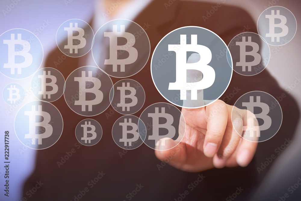 Bitcoin button on virtual interface displaying, businessman touching the currency symbol. Bitcoin button on virtual interface displaying, businessman touching the currency symbol.