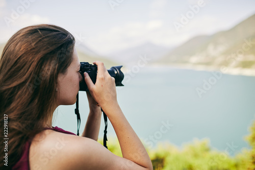 Young tourist Girl taking pictures of mountains and lake. Georgia. Summer. August.