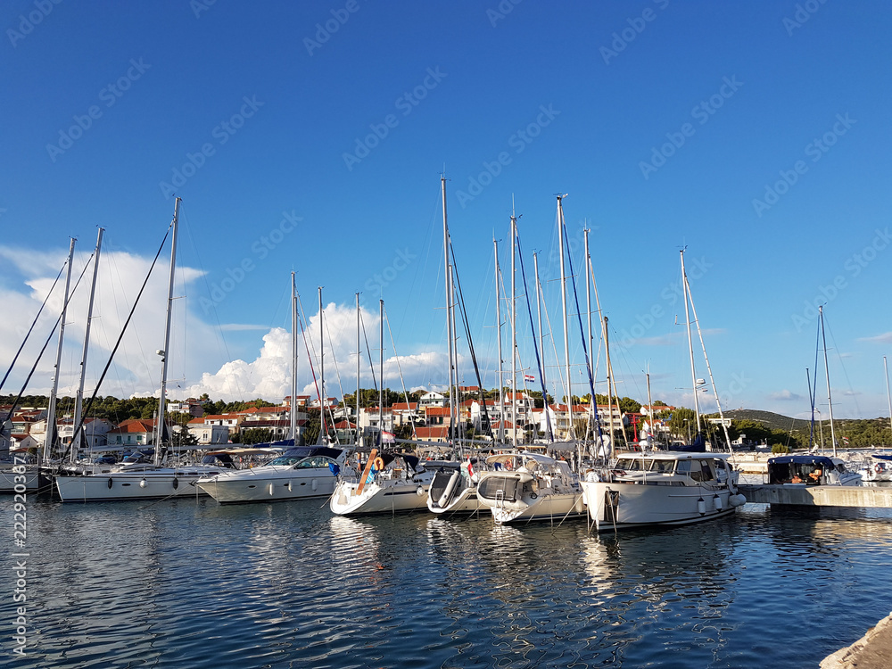 Panorama of a yacht marina in the town of Jezera in Croatia in the Dalmatia region. The ships moored in the port of a quiet fishing town in a sunny, clear day. Tourist marine business. Rest by sea