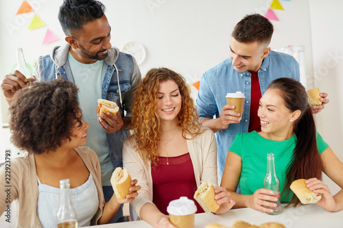 corporate  celebration and people concept - happy friends or team eating sandwiches with coffee and non-alcoholic drinks at office party