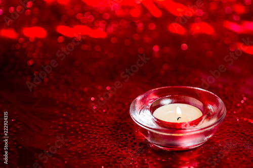 Burning red tea light candle on Christmas decoration colorful glitter red bokeh background