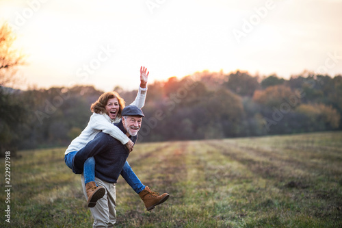 Senior man giving a woman a piggyback ride in an autumn nature. photo