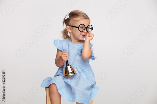 liitle girl wearing glasses and holding bell looks to side