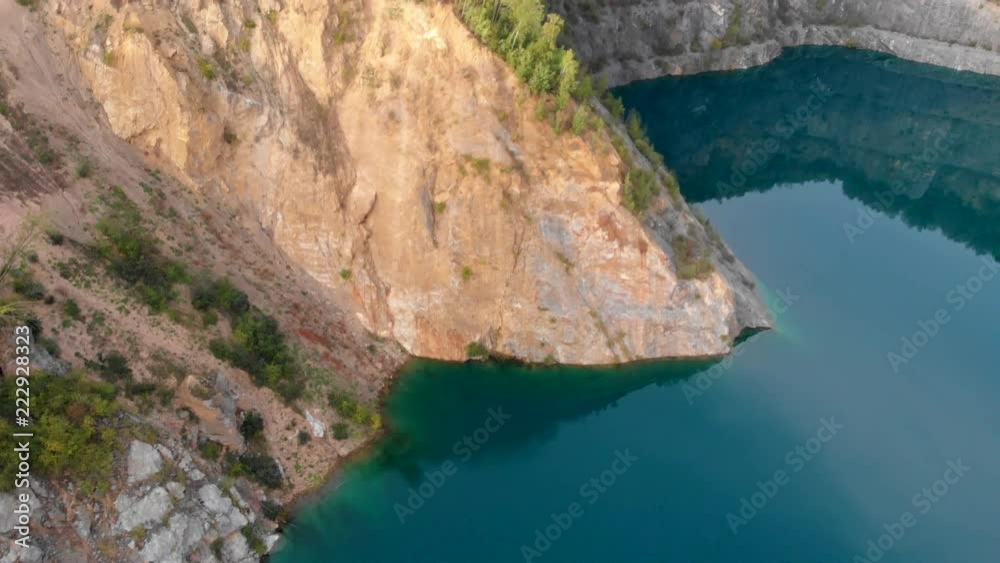 (Luftaufnahme, Drohne) Schwenk über steile Felswand mit blauem See im Vordergrund (Luftaufnahme, Drohne) Schwenk über steile Felswand mit blauem See im Vordergrund