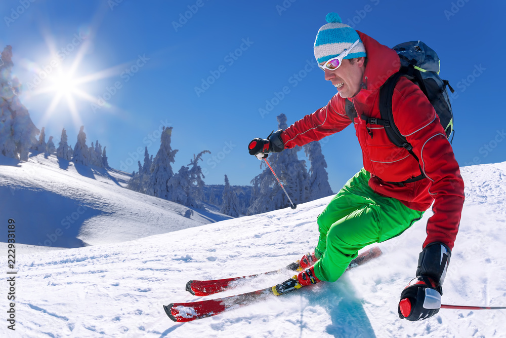 Skier skiing downhill in high mountains against blue sky