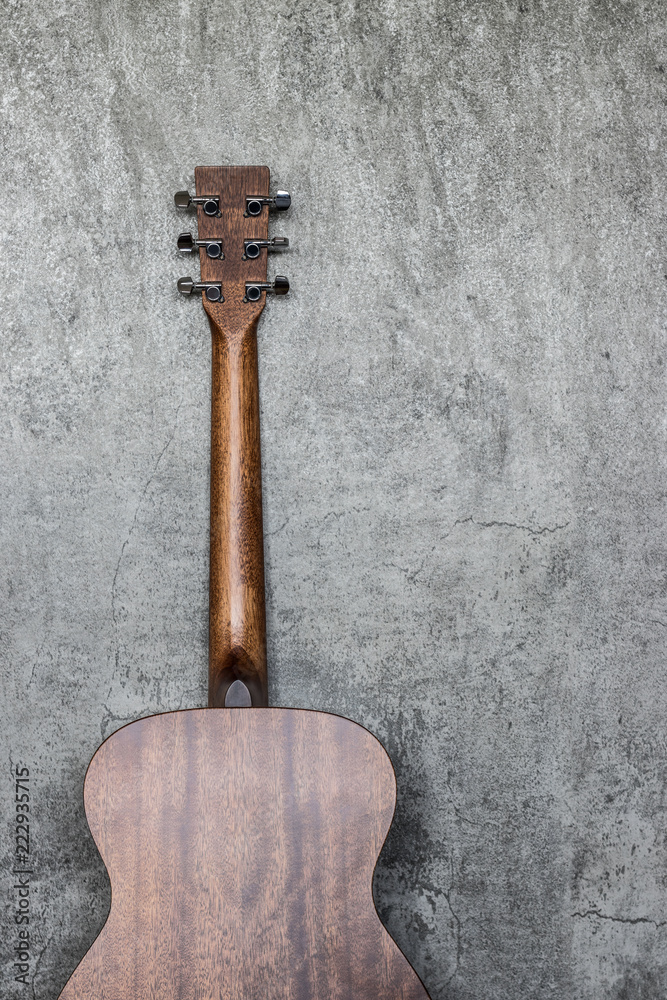 Obraz premium back of acoustic guitar lean against cement wall