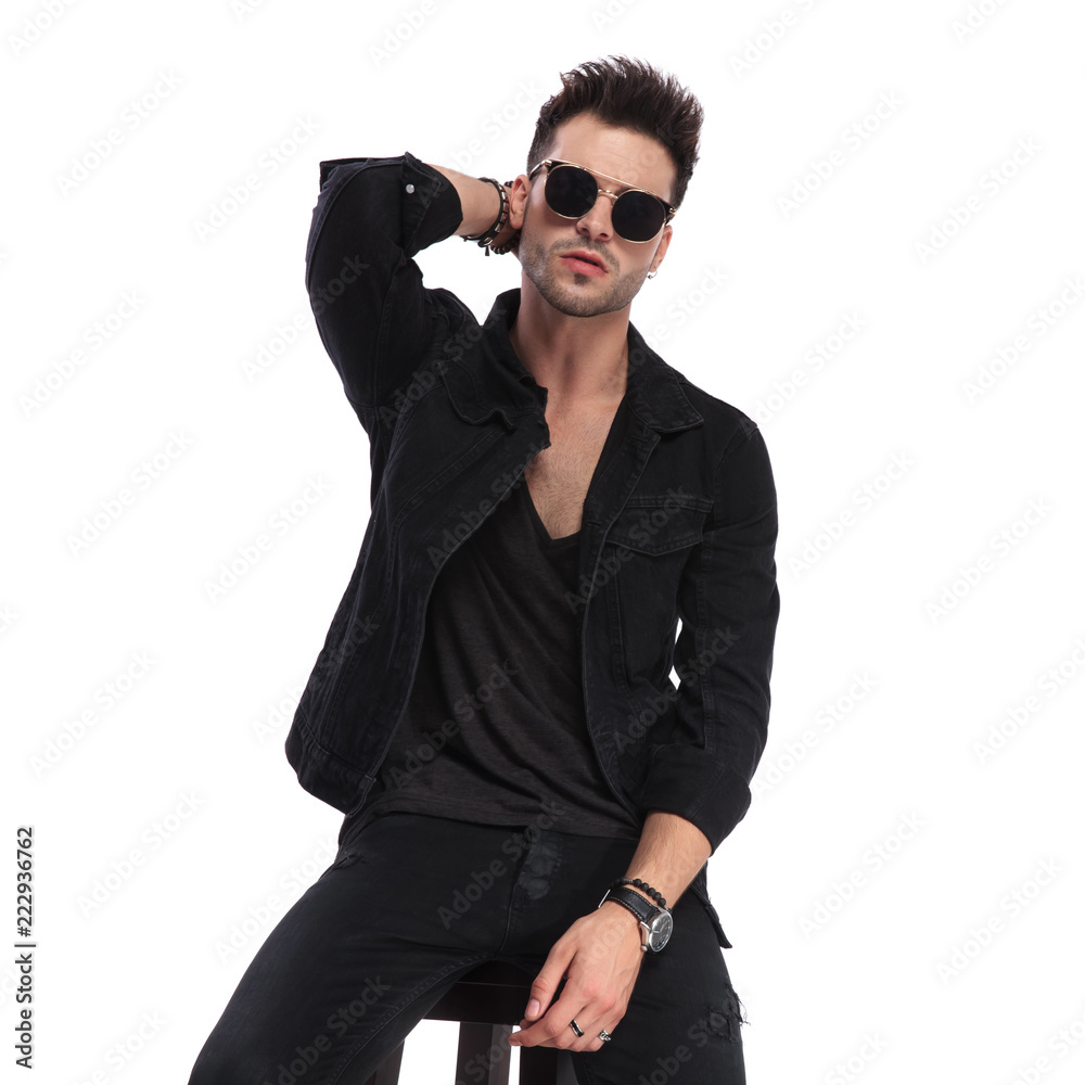seductive seated man wearing sunglasses arranging his hair seductive seated man wearing sunglasses arranging his hair