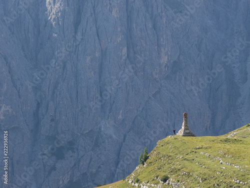 Denkmal vor riesiger Felswand mit fotografierendem Touristen, 3 Zinnen Tour, Südtirol, Italien photo