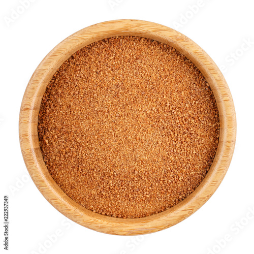 Organic coconut unrefined sugar in wooden bowl isolated on white. Top view. photo