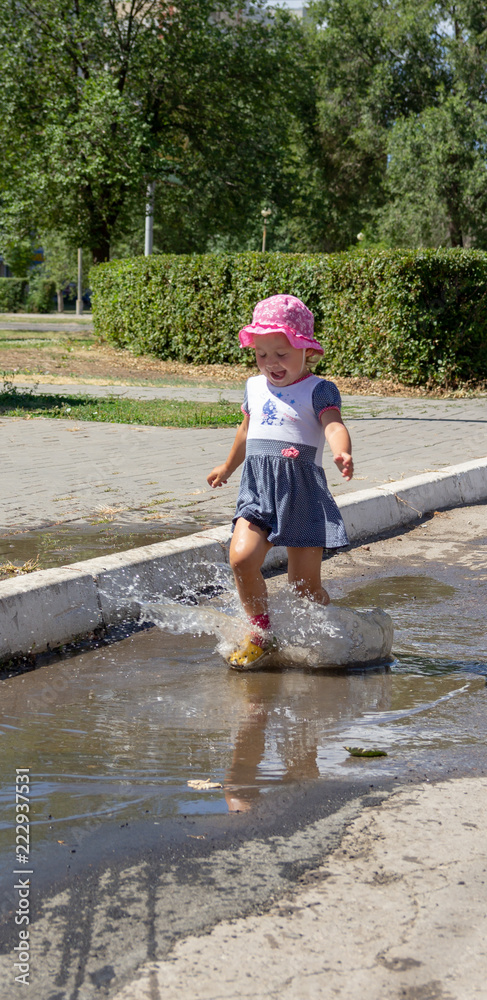 Cute baby sports and runs through the puddles on a summer sunny day Cute baby sports and runs through the puddles on a summer sunny day
