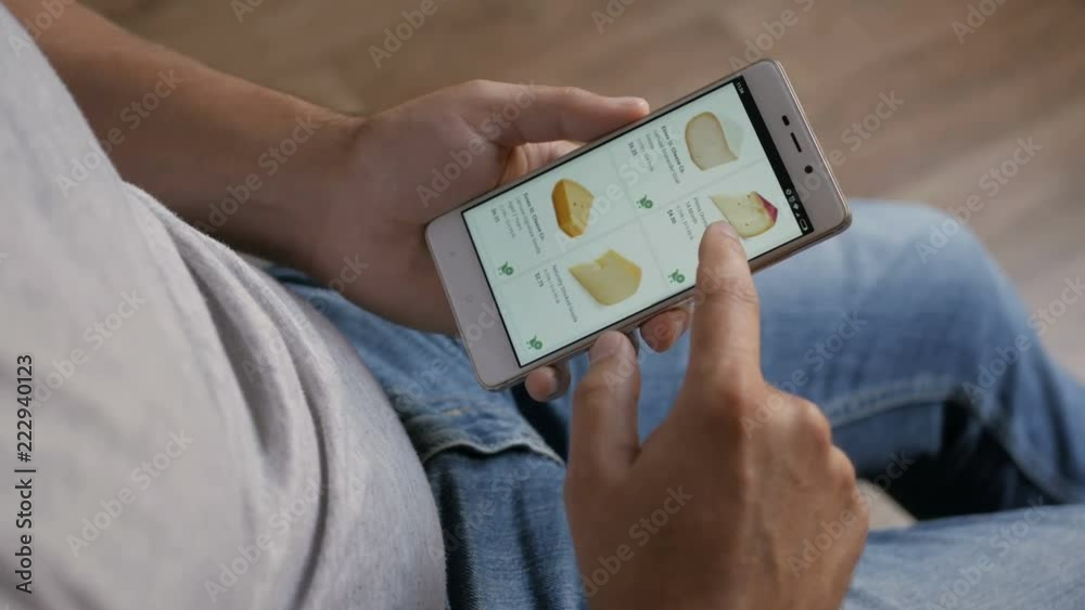 Man orders food home in an online store using a smartphone. Male selects the cheese in the grocery online store using smartphone. Close-up. 4K UHD. LOS ANGELES - September 2018.