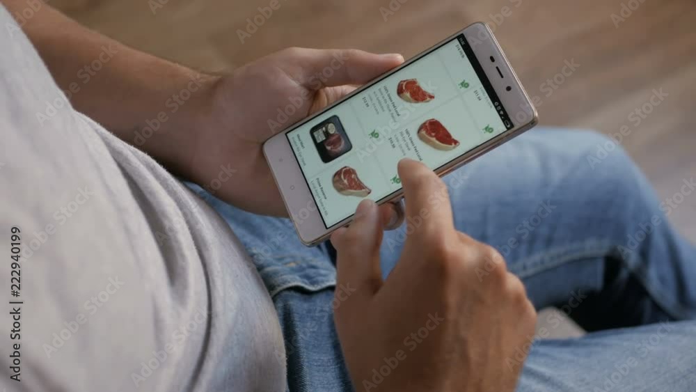 Man orders food home in an online store using a smartphone. Male selects the meat in the grocery online store using smartphone. Close-up. 4K UHD. LOS ANGELES - September 2018.