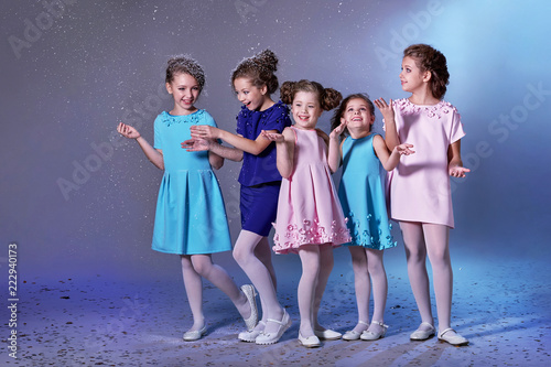 Group happy children in celebratory clothes for lady girls. Concept fashion, holiday, christmas, new year, x-mas, winter. Five kids in beautiful dresses enjoying snow on eve new year. Studio shot.