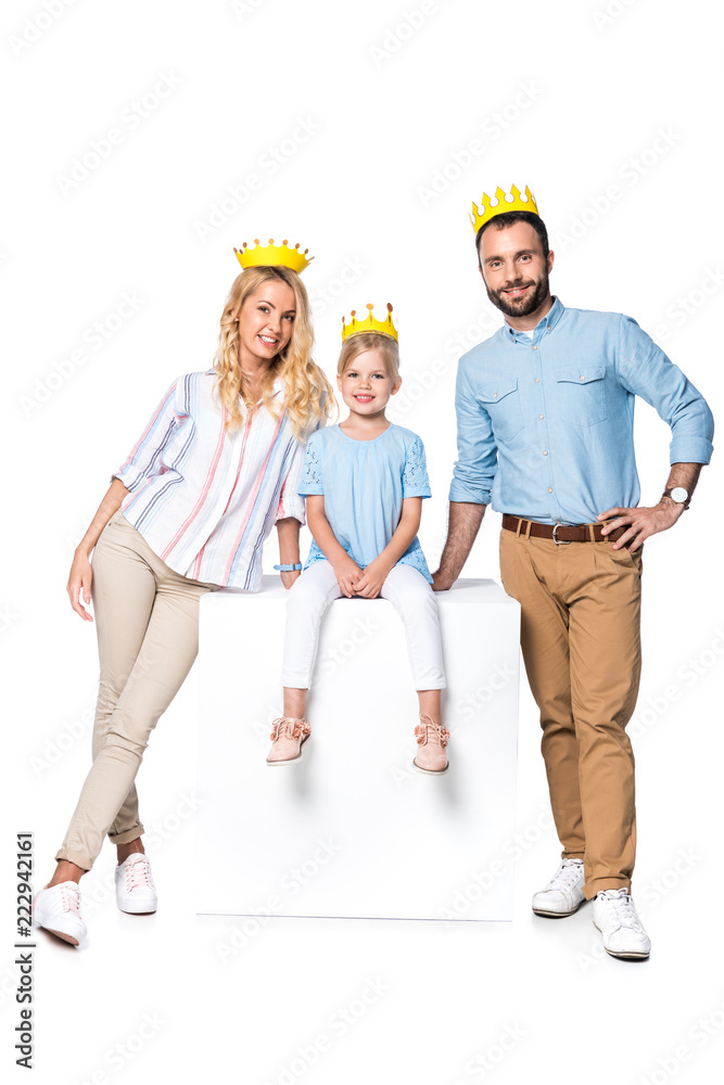 happy family with cardboard crowns sitting on white cube isolated on white happy family with cardboard crowns sitting on white cube isolated on white