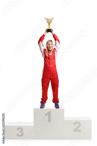 Happy female racer celebrating win on a winner's pedestal with a gold trophy cup
