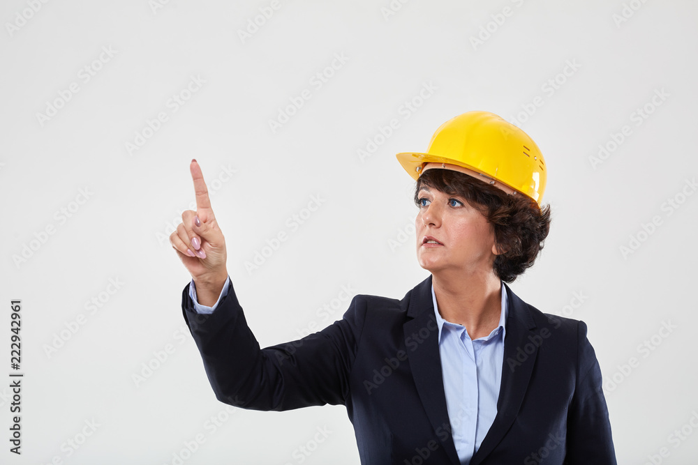Mature engineer lady in hard hat indicating Mature engineer lady in hard hat indicating