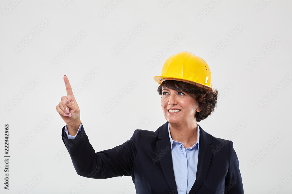 Mature engineer lady in hard hat indicating