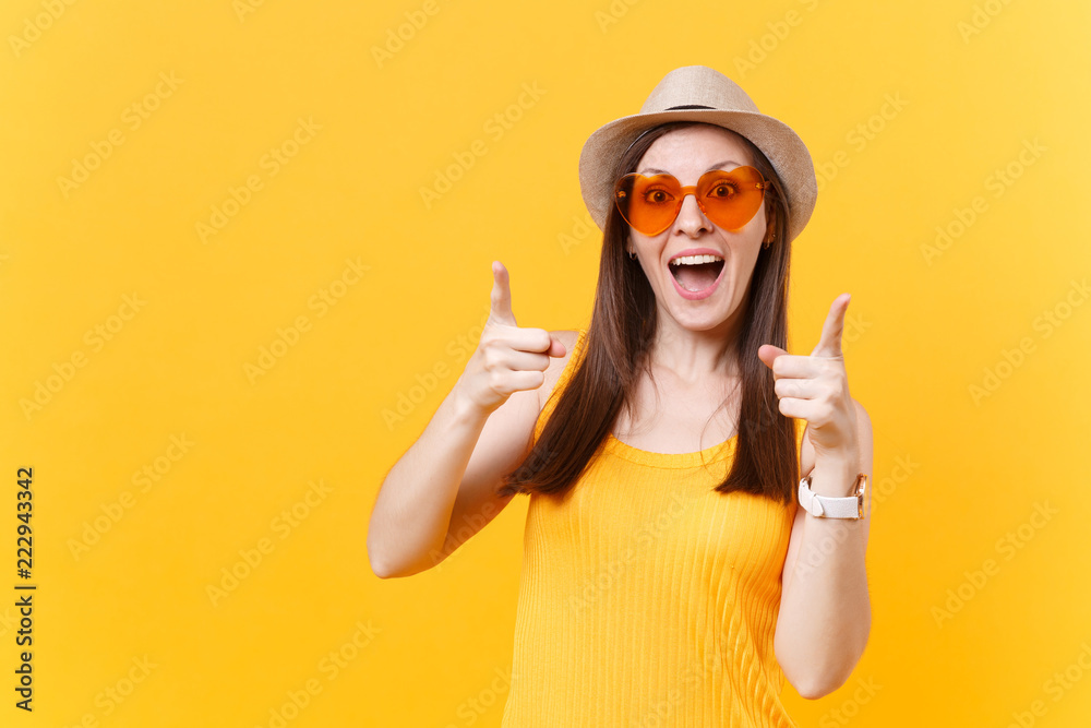 Portrait of overjoyed young woman in straw summer hat, orange glasses poining fingers camera, copy space isolated on yellow background. People sincere emotions, lifestyle concept. Advertising area. Portrait of overjoyed young woman in straw summer hat, orange glasses poining fingers camera, copy space isolated on yellow background. People sincere emotions, lifestyle concept. Advertising area.