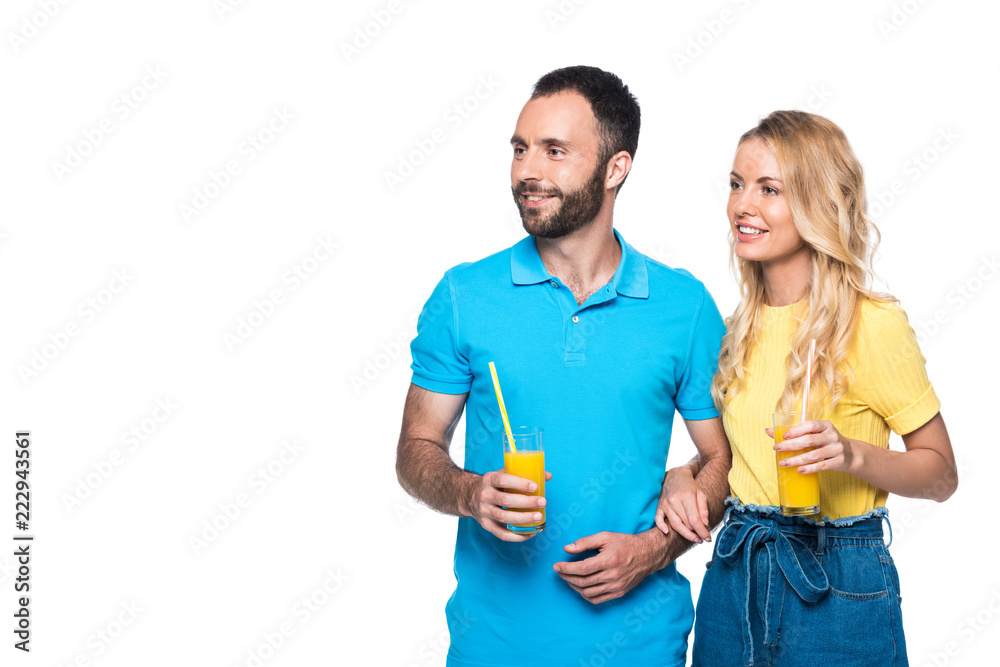 Fototapeta premium couple holding glasses with orange juice and looking away isolated on white