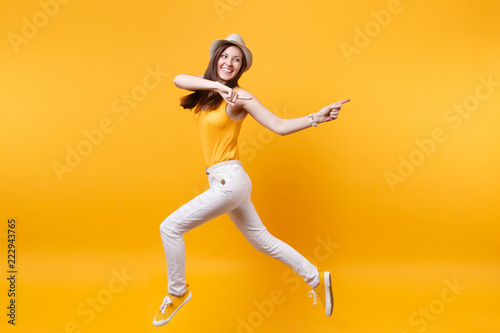 Portrait of excited smiling young happy jumping high woman in straw summer hat, copy space isolated on yellow orange background. People sincere emotions, passion lifestyle concept. Advertising area.