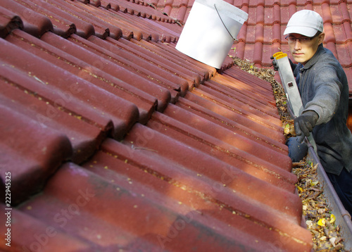 The man cleans the gutters on the roof