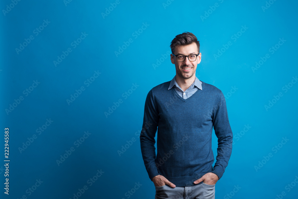 Portrait of a young man with glasses in a studio on a blue background. Portrait of a young man with glasses in a studio on a blue background.