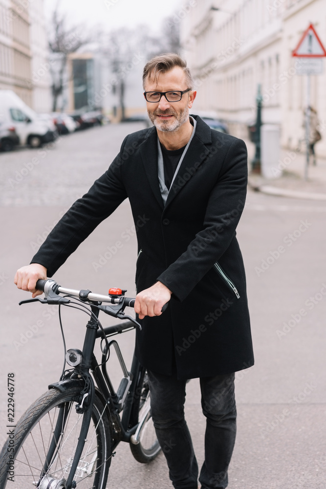Mature man standing with bicycle in street Mature man standing with bicycle in street