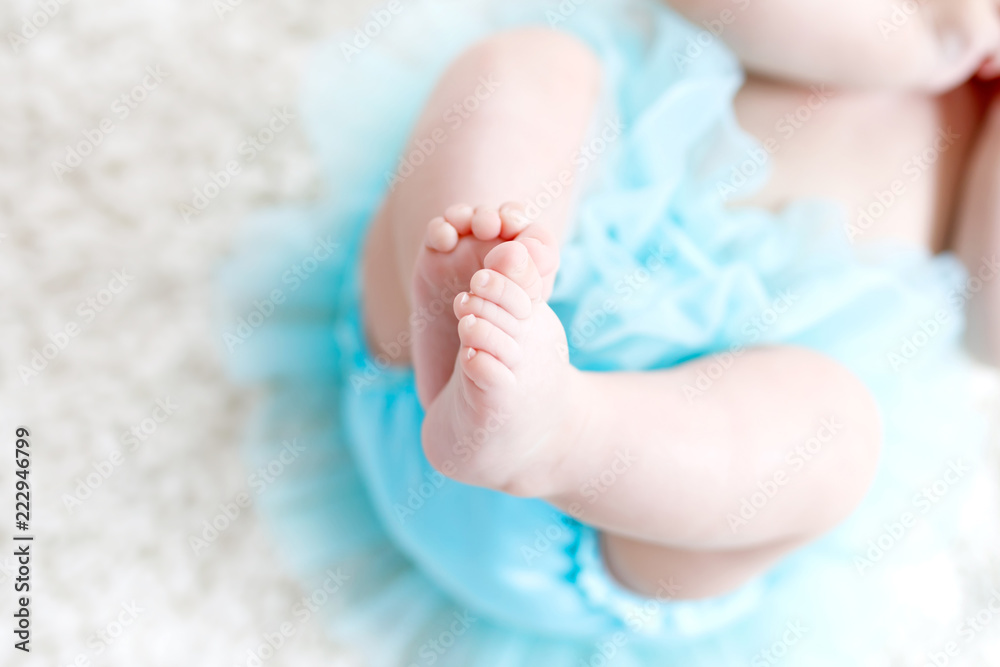 Close-up of legs and feet of baby girl on white background wearing turquoise tutu skirt. Close-up of legs and feet of baby girl on white background wearing turquoise tutu skirt.
