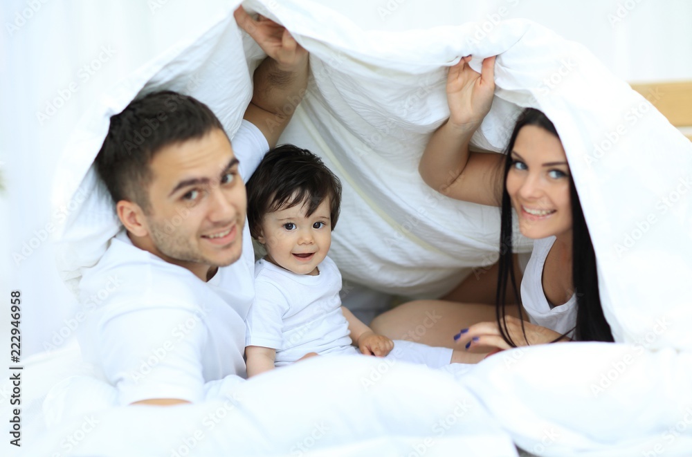 Families with children in bed under a blanket