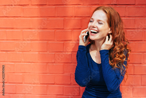 Laughing woman holding smart phone to her ear