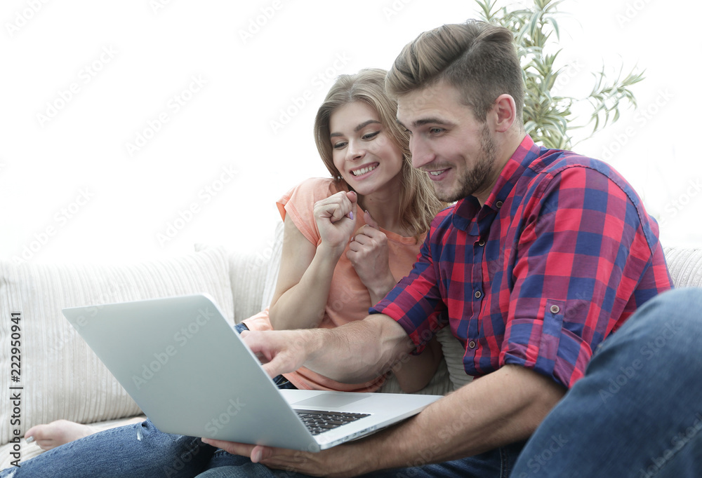smiling young couple with laptop sitting on the couch