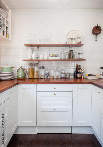 wooden kitchen countertop with white cupboards and food ingrediens 
