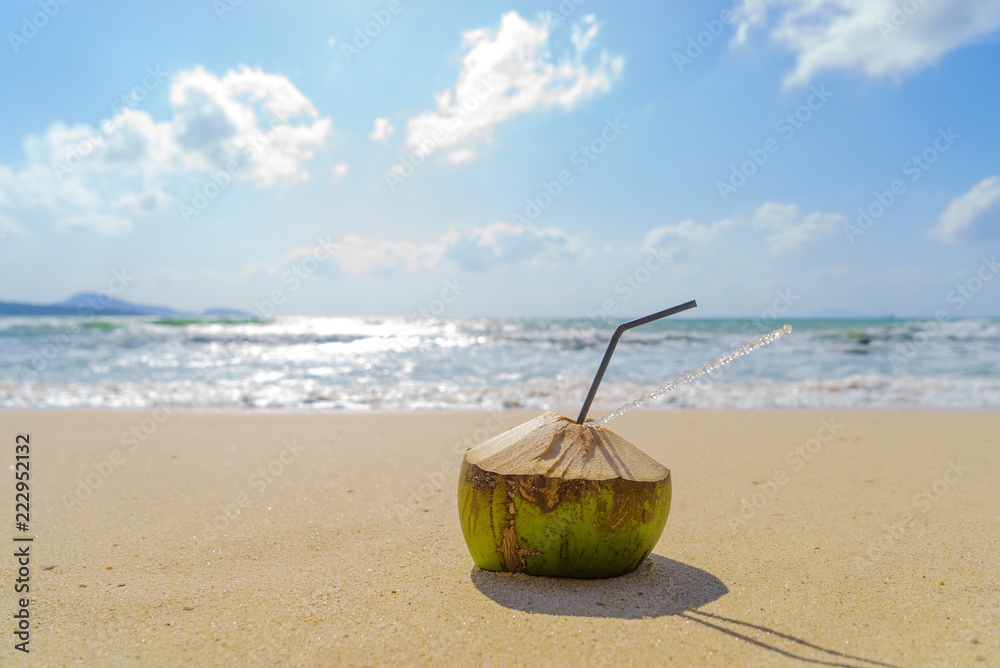 Coconut with drinking straw on beach Coconut with drinking straw on beach