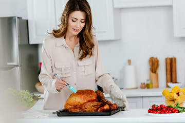 attractive happy woman cooking thanksgiving turkey at kitchen