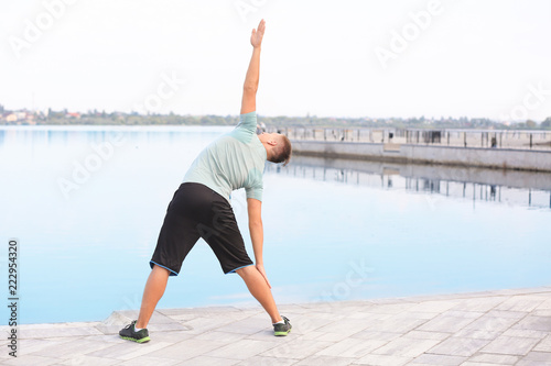 Sporty young man training outdoors near river