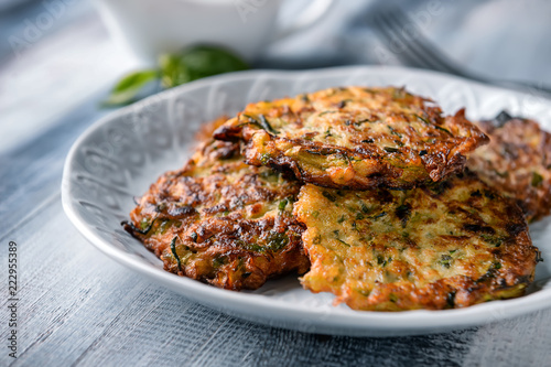 Plate with tasty zucchini pancakes on wooden table, closeup