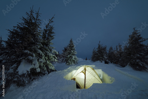 Camping tent in a winter mountain forest