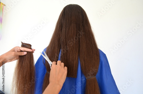 Стрижка на длинных волосах, парикмахер обрезает прядь волос