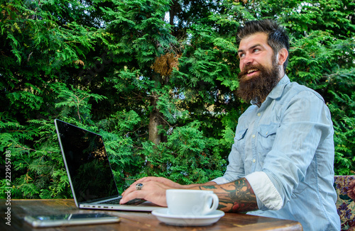 Hipster freelancer work online blog notebook. Man bearded businessman sit terrace with laptop and cup of coffee. Freelance benefit. Create content for web blog. Blogger create post while enjoy coffee