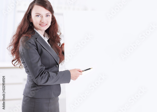 business woman with a pencil pointing at a blank poster.