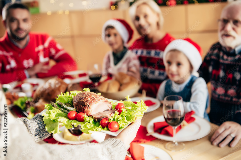 partial view of woman carrying meal for christmas dinner with family at home