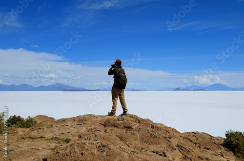 One male tourist taking photos of the imense Uyuni salt flats from Isla Incahuasi, the outcrop  in the middle of the salt flats, Potosi, Bolivia photo